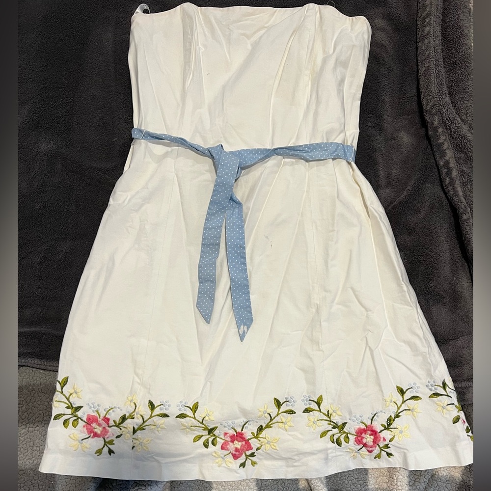 White strapless Shoshanna dress with flower trim on bottom and blue gingham belt